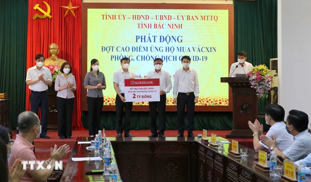 Đại diện lãnh đạo tỉnh Bắc Ninh tiếp nhận 2 tỷ đồng của Ngân hàng Nông nghiệp và Phát triển nông thôn chi nhánh Bắc Ninh. (Ảnh: Thái Hùng/TTXVN)