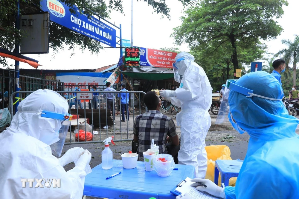  Lấy mẫu xét nghiệm SARS-CoV-2 các tiểu thương bán hàng trong chợ Xanh Văn Quán, Hà Nội. (Ảnh: TTXVN)