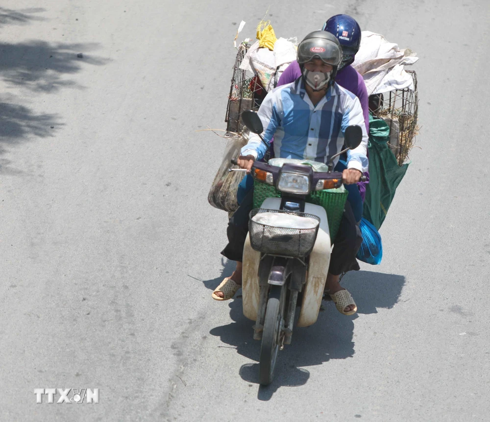 Thời điểm giữa trưa, nếu phải di chuyển trên đường, người dân cần trang bị đồ chống nắng để đảm bảo sức khỏe. (Ảnh: Thanh Tùng/TTXVN)