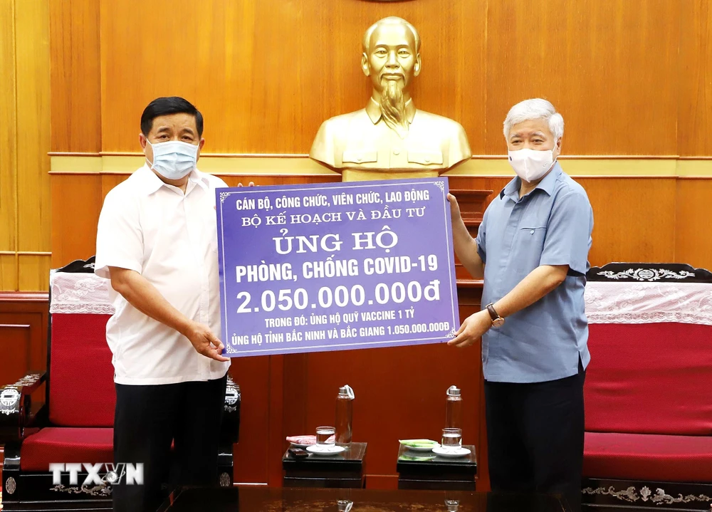 Chủ tịch Ủy ban Trung ương Mặt trận Tổ quốc Việt Nam Đỗ Văn Chiến tiếp nhận ủng hộ Quỹ vaccine phòng COVID-19 từ Bộ trưởng Bộ Kế hoạch và Đầu tư Nguyễn Chí Dũng. (Ảnh: Minh Đức/TTXVN)