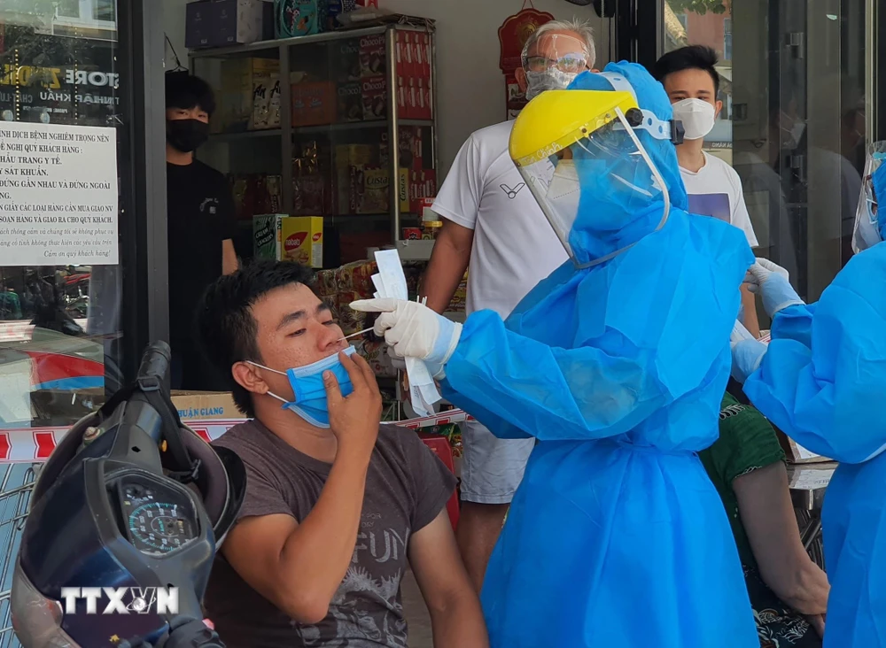 Nhân viên y tế lấy mẫu xét nghiệm của người dân quanh khu vực có ca mắc COVID-19 tại đường Lê Duẩn, Đà Nẵng. (Ảnh: Văn Dũng/TTXVN)