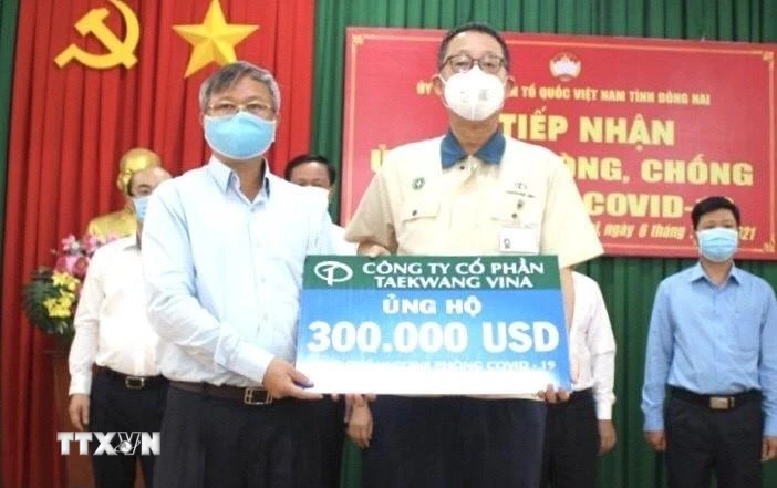 Chủ tịch UBND tỉnh Đồng Nai Cao Tiến Dũng (trái) tiếp nhận 300.000 USD từ Đại diện Công ty cổ phần Taekwang Vina ủng hộ Quỹ vaccine phòng, chống dịch COVID-19. (Ảnh: TTXVN phát)