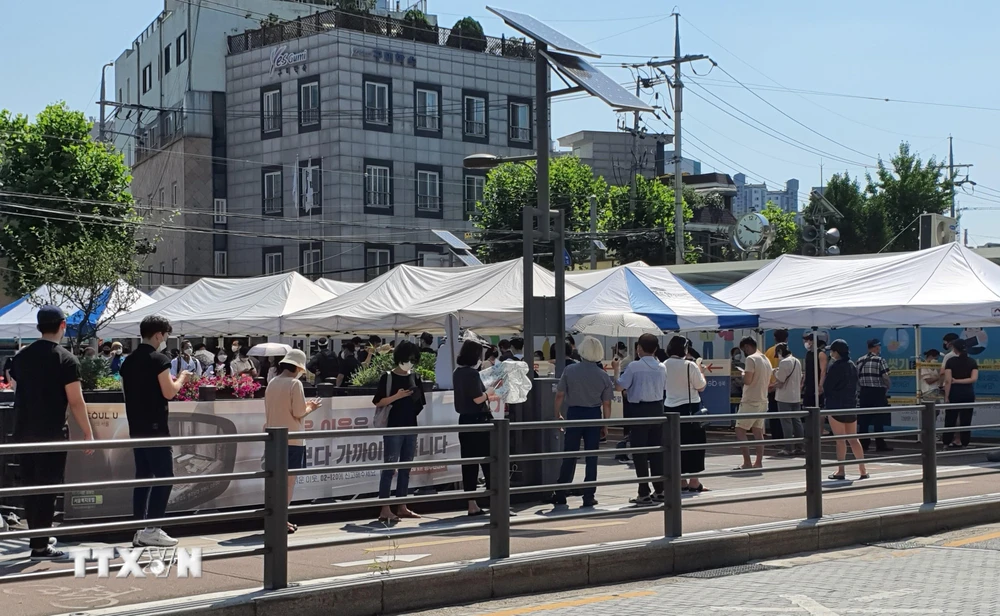 Người dân xếp hàng xét nghiệm COVID-19 trong thời tiết nắng nóng ở quận Seongbuk, Seoul. (Ảnh: Mạnh Hùng/TTXVN)