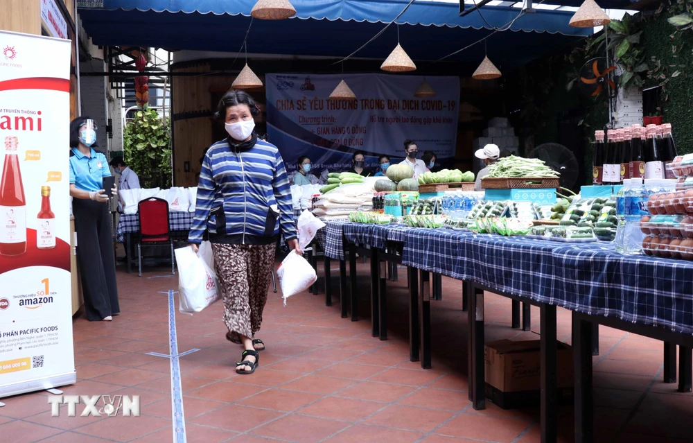 Người dân nghèo TP Hồ Chí Minh nhận nhu yếu phẩm, lương thực khi đến với Siêu thị 0 đồng. (Ảnh: Xuân Khu/TTXVN)