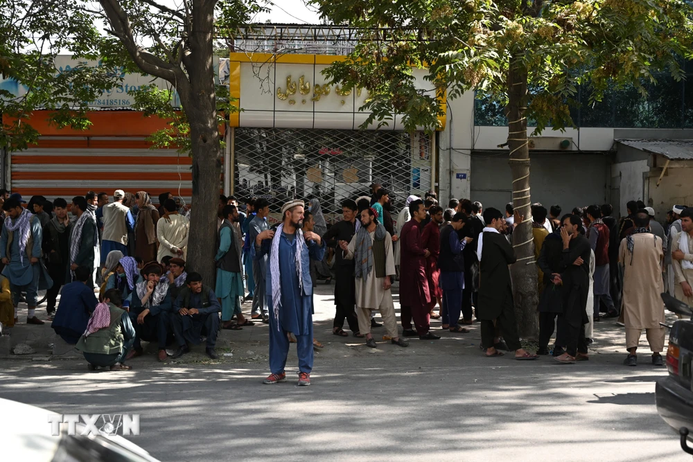 Người dân đợi bên ngoài một ngân hàng đóng cửa ở Kabul, Afghanistan, ngày 28/8/2021. (Ảnh: AFP/TTXVN)