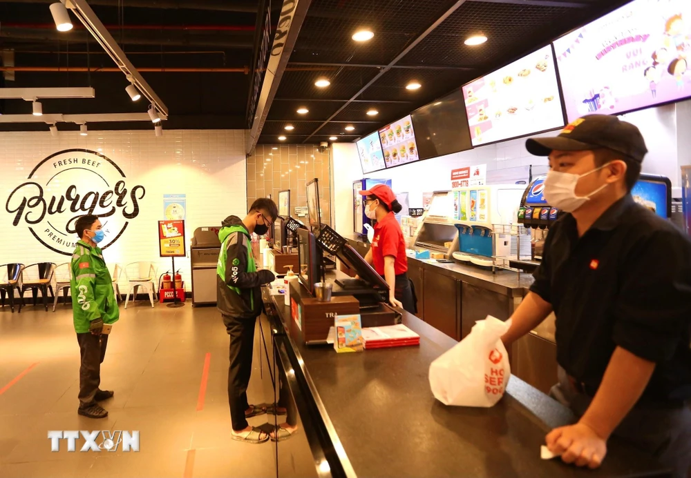 Các cửa hàng ăn, uống trong TTTM BigC Thăng Long (Hà Nội) yêu cầu khách hàng đứng giãn cách và chỉ bán hàng mang về. (Ảnh: Hoàng Hiếu/TTXVN)