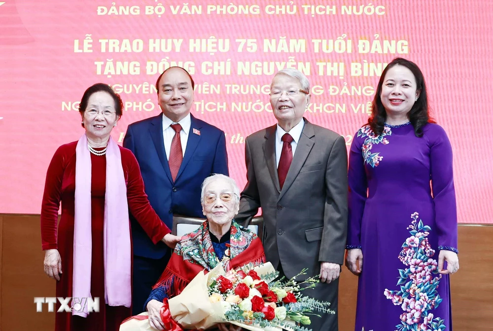 Chủ tịch nước Nguyễn Xuân Phúc và các đại biểu tại Lễ trao tặng huy hiệu 75 năm tuổi Đảng cho bà Nguyễn Thị Bình, nguyên Ủy viên Trung ương Đảng, nguyên Phó Chủ tịch nước CHXHCN Việt Nam. (Ảnh: Thống Nhất/TTXVN)