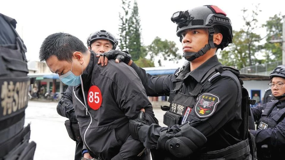 Một nghi phạm lừa đảo bị cảnh sát Trung Quốc áp giải. (Ảnh: China Daily) 