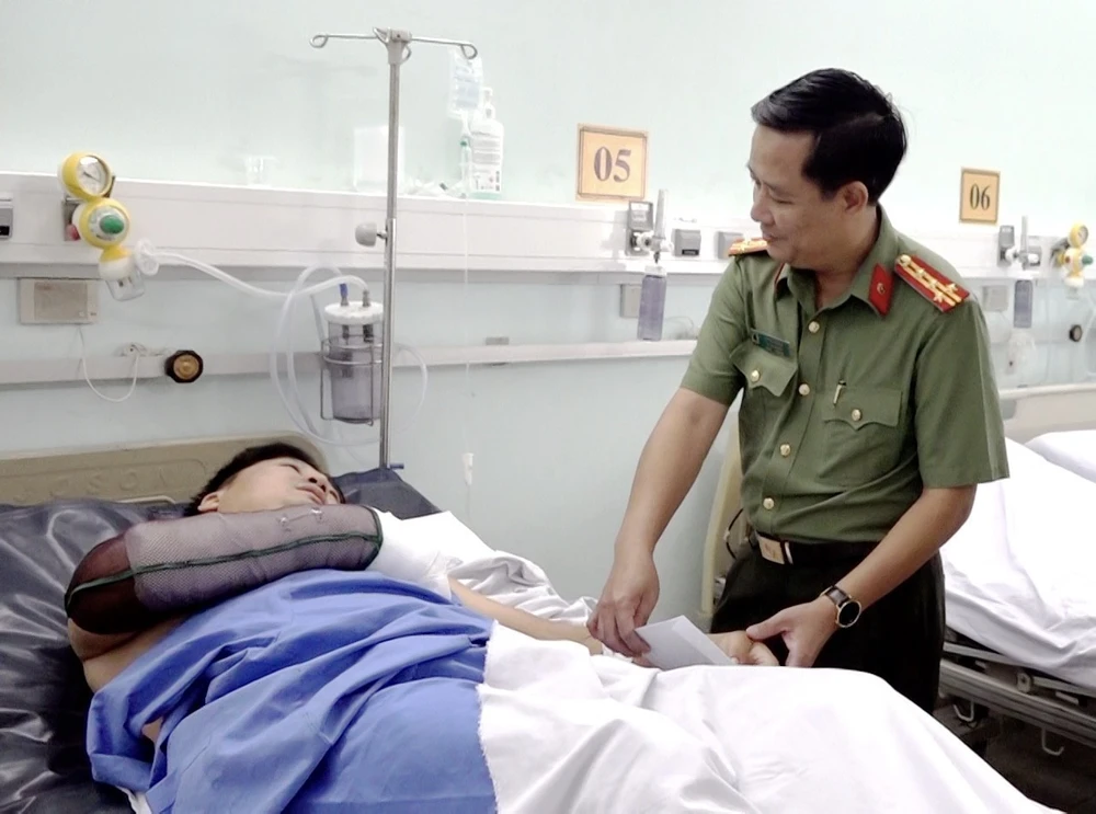 Đại tá Lê Phú Thạnh, Phó Giám đốc Công an tỉnh An Giang thăm hỏi, động viên Thiếu tá Thái Văn Tâm bị thương khi làm nhiệm vụ. (Ảnh: Thanh Sang/TTXVN)