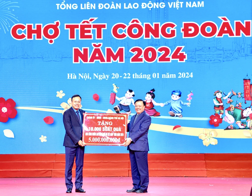 Ông Đinh Tiến Dũng, Ủy viên Bộ Chính trị, Bí thư Thành ủy Hà Nội trao biển tượng trưng kinh phí tặng quà Tết cho đoàn viên, người lao động. (Ảnh: Minh Nghĩa/TTXVN)