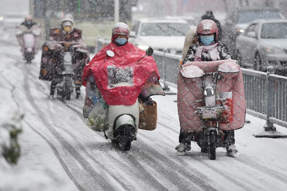 Người dân di chuyển trên đường phố trong thời tiết giá lạnh tại Hoài An, tỉnh Giang Tô, Trung Quốc. (Ảnh: AFP/TTXVN)
