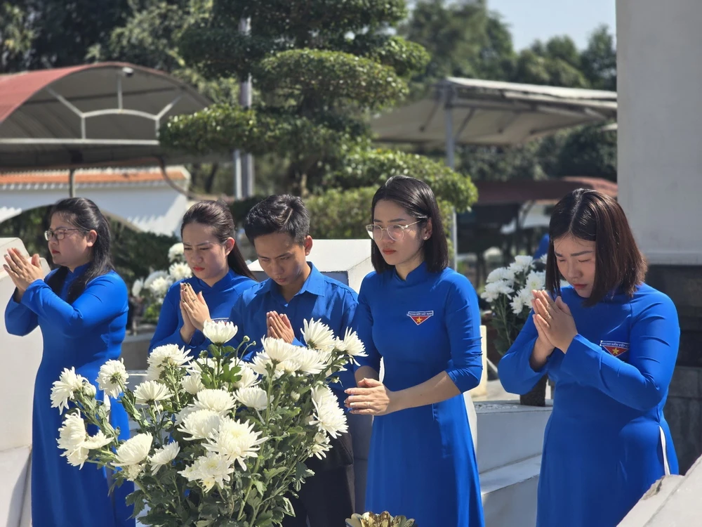 Nữ công Thành đoàn Hà Tĩnh trong trang phục áo dài truyền thống dâng hương tại Khu mộ 10 liệt sỹ thanh niên xung phong Ngã ba Đồng Lộc. (Ảnh: TTXVN phát)
