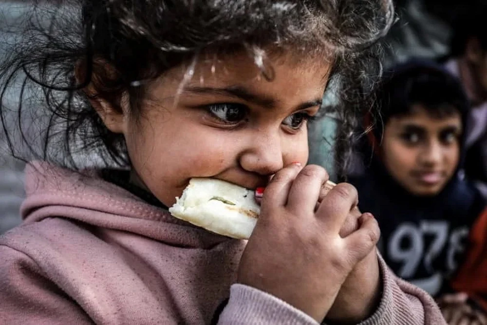 Một em bé Palestine ăn bánh mỳ trong một trại tị nạn thành phố Rafah, phía nam Dải Gaza. (Ảnh: DPA)