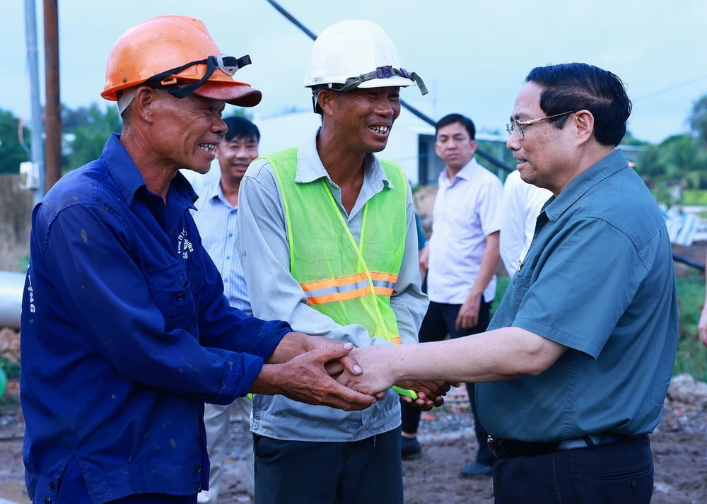 Thủ tướng Phạm Minh Chính với công nhân thi công tuyến đường Cao tốc Châu Đốc-Cần Thơ-Sóc Trăng đoạn đi qua xã Đông Thắng, huyện Cờ Đỏ. (Ảnh: Dương Giang/TTXVN)