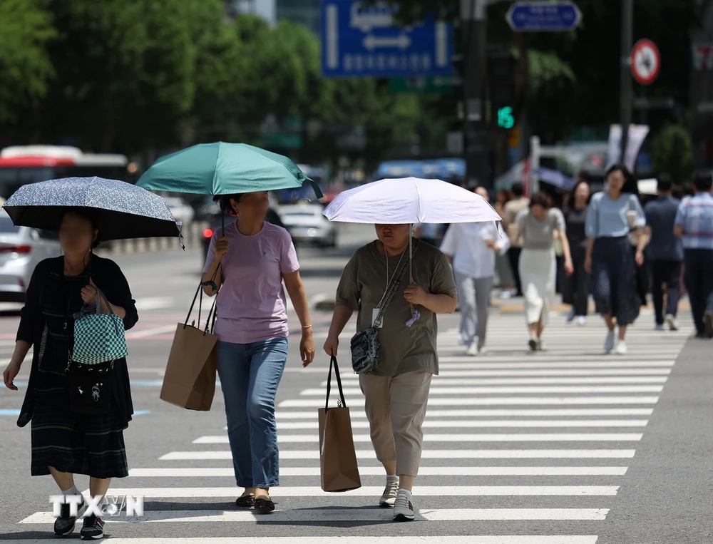 Người dân di chuyển trên đường phố dưới trời nắng nóng tại Seoul, Hàn Quốc, ngày 17/6/2024. (Ảnh: Yonhap/TTXVN)