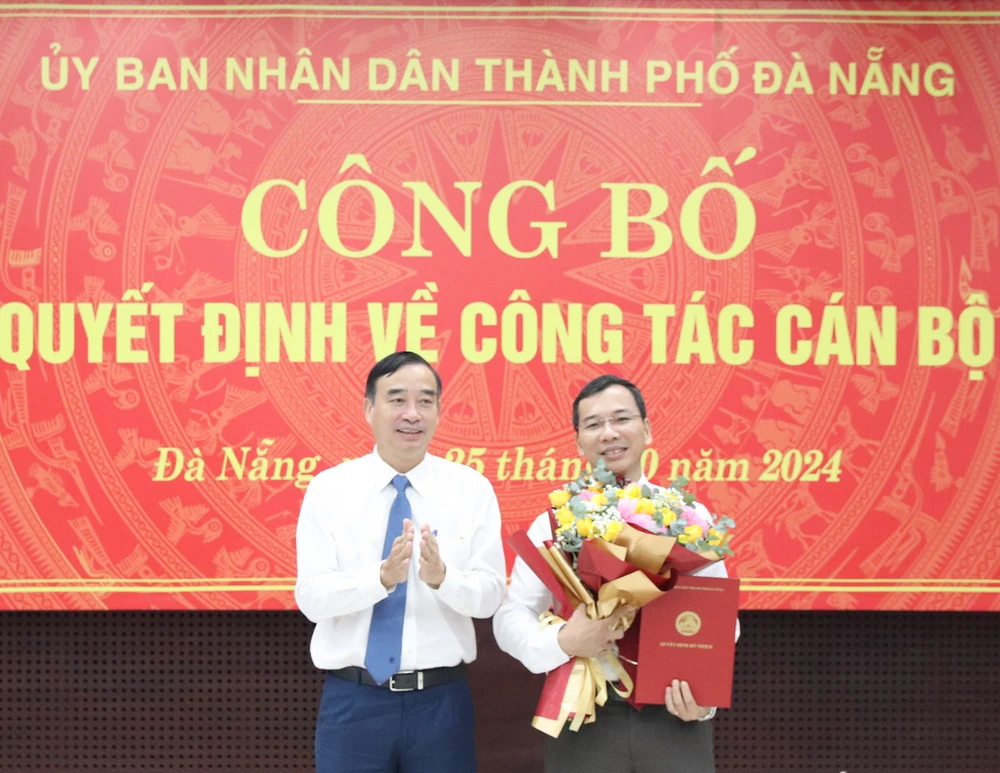 Chủ tịch UBND thành phố Lê Trung Chinh (trái) trao quyết định, tặng hoa chúc mừng tân Giám đốc Sở Nội vụ kiêm Chủ tịch UBND huyện Hoàng Sa, ông Nguyễn Hữu Lợi. (Ảnh: Báo Đà Nẵng)