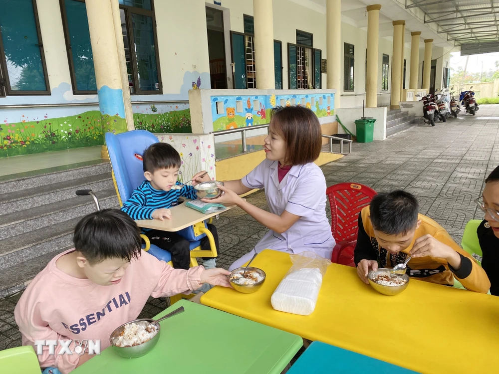 Các cô giáo tại Làng Trẻ em Mồ côi Hà Tĩnh chăm sóc trẻ trong giờ ăn trưa. (Ảnh: Hữu Quyết/TTXVN)