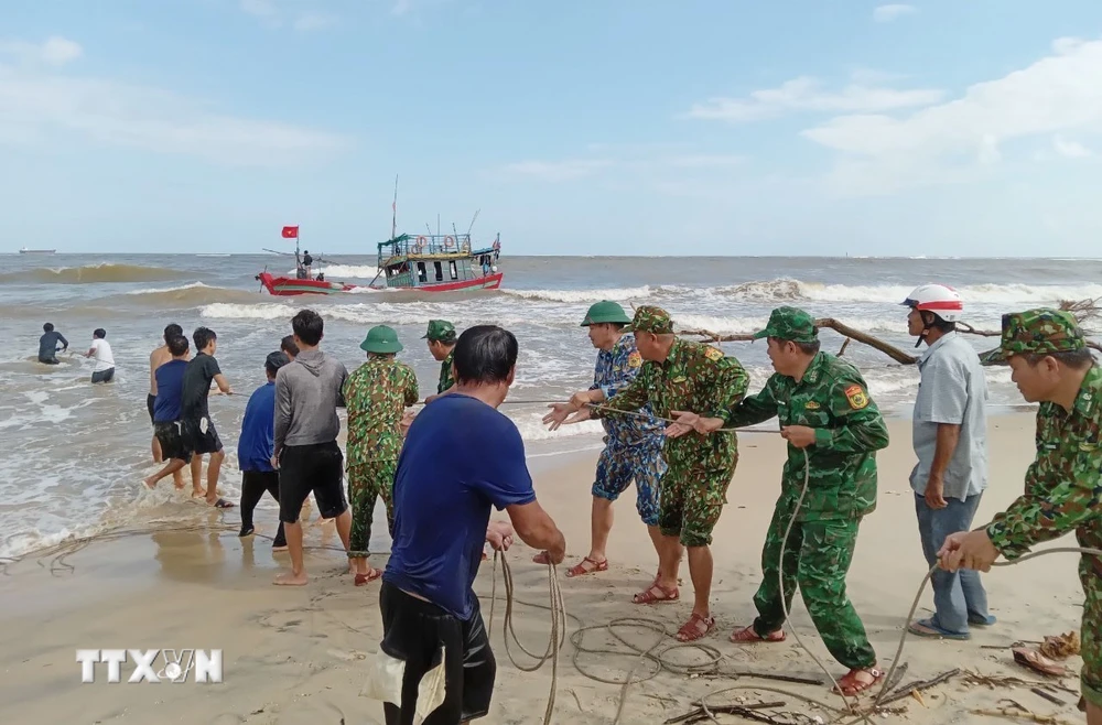 Bộ đội Biên phòng tỉnh Quảng Trị hỗ trợ ngư dân cố định tàu cá mắc cạn. (Ảnh: TTXVN phát) 