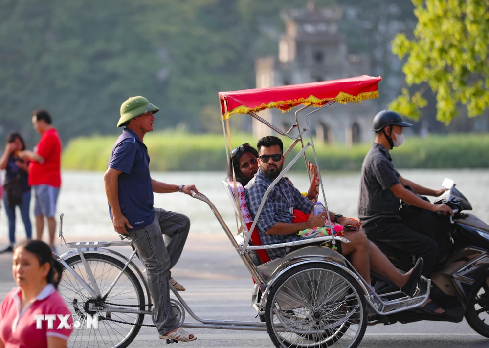 Du khách quốc tế trên xe xích lô đi tham quan phố cổ, Hồ Hoàn Kiếm ở Hà Nội. (Ảnh: Thanh Tùng/TTXVN)