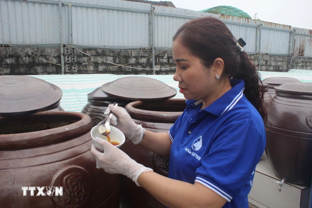 Chị Nguyễn Thị Thơm, làng nghề Do Xuyên-Ba Làng, kiểm tra chất lượng nước mắm trước khi cung ứng cho thị trường Tết. (Ảnh: Nguyễn Nam/TTXVN)