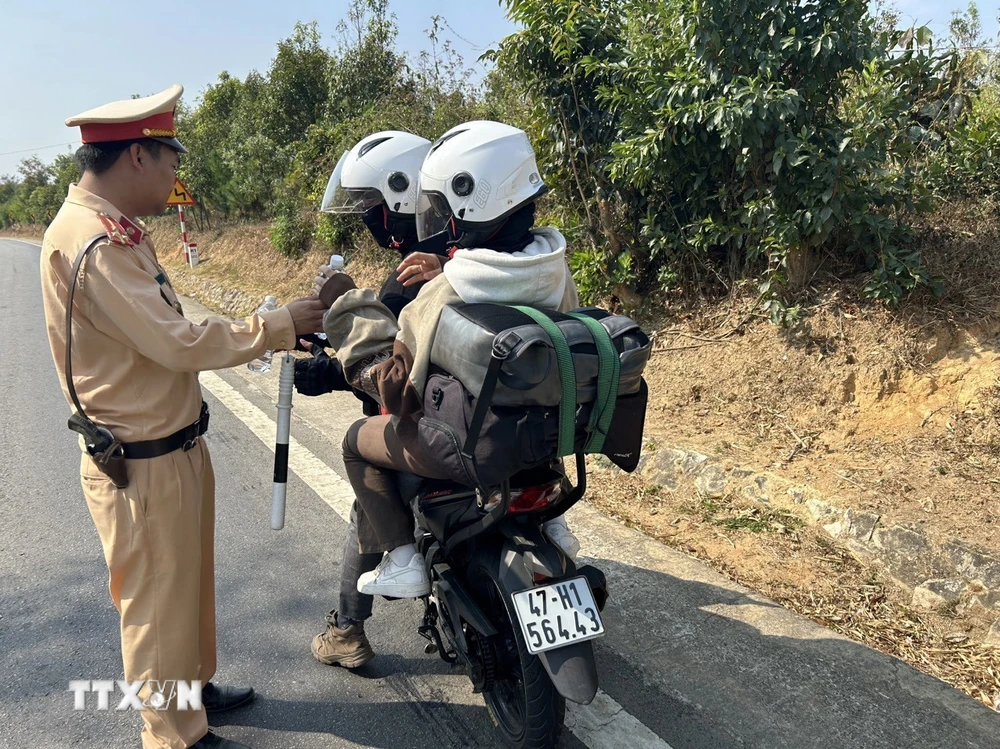 Cảnh sát giao thông tại chốt Sao Mai tặng nước uống miễn phí cho người dân khi đi qua địa bàn tỉnh Kon Tum về quê đón Tết. (Ảnh: TTXVN phát)