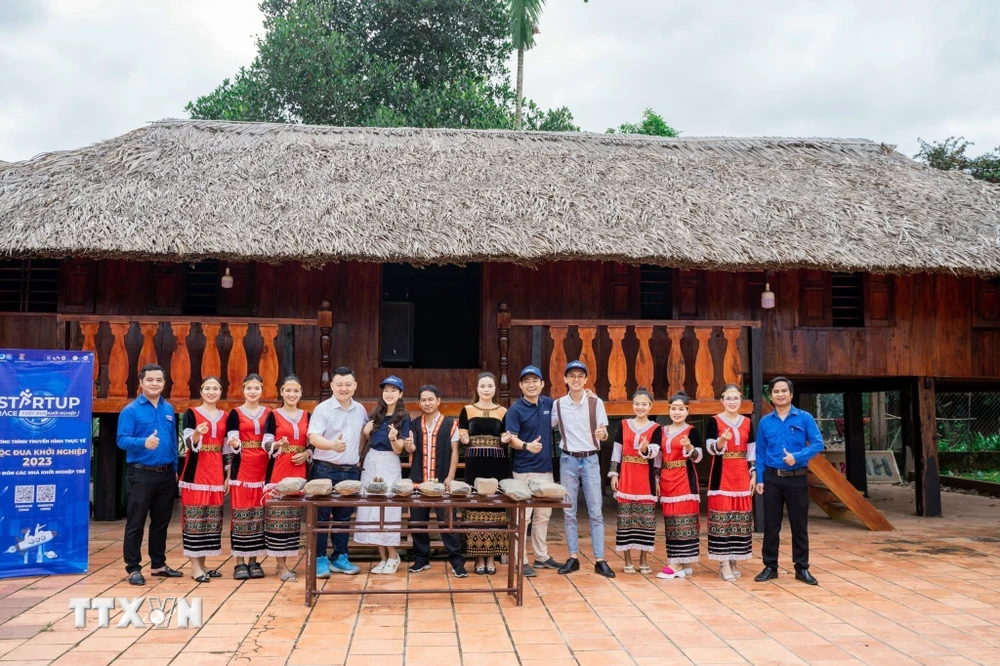 Nhóm các bạn trẻ Khanh Son Eco cùng đoàn khách du lịch chụp ảnh lưu niệm tại nhà dài của người đồng bào dân tộc Raglai, nhằm giới thiệu một sản phẩm văn hóa của huyện Khánh Sơn. (Ảnh: TTXVN phát)