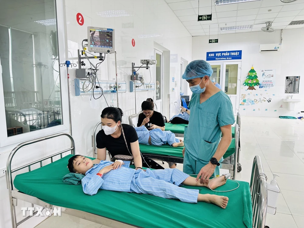 Bác sỹ Trần Minh Long kiểm tra sức khỏe bệnh nhi sau ca phẫu thuật. (Ảnh: Bích Huệ/ TTXVN)