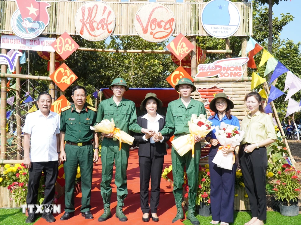 Hai anh em Nguyễn Tiến Thành và Nguyễn Tiến Đạt chụp ảnh lưu niệm cùng lãnh đạo huyện Phú Riềng và Ban Chỉ huy Quân sự huyện. (Ảnh: TTXVN phát)