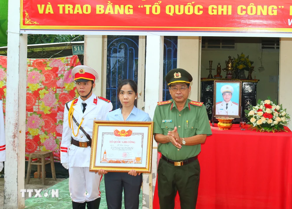 Đại tá Nguyễn Văn Hiểu trao Bằng Tổ quốc ghi công cho vợ Liệt sỹ Hồ Tấn Dương. (Ảnh: TTXVN phát)