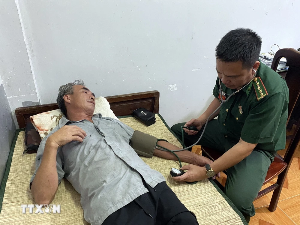 Cán bộ Quân y Đồn Biên phòng Cửa khẩu Cảng Gianh thăm khám sức khỏe ban đầu cho thuyền viên bị nạn Nguyễn Văn Bình. (Ảnh: TTXVN phát)