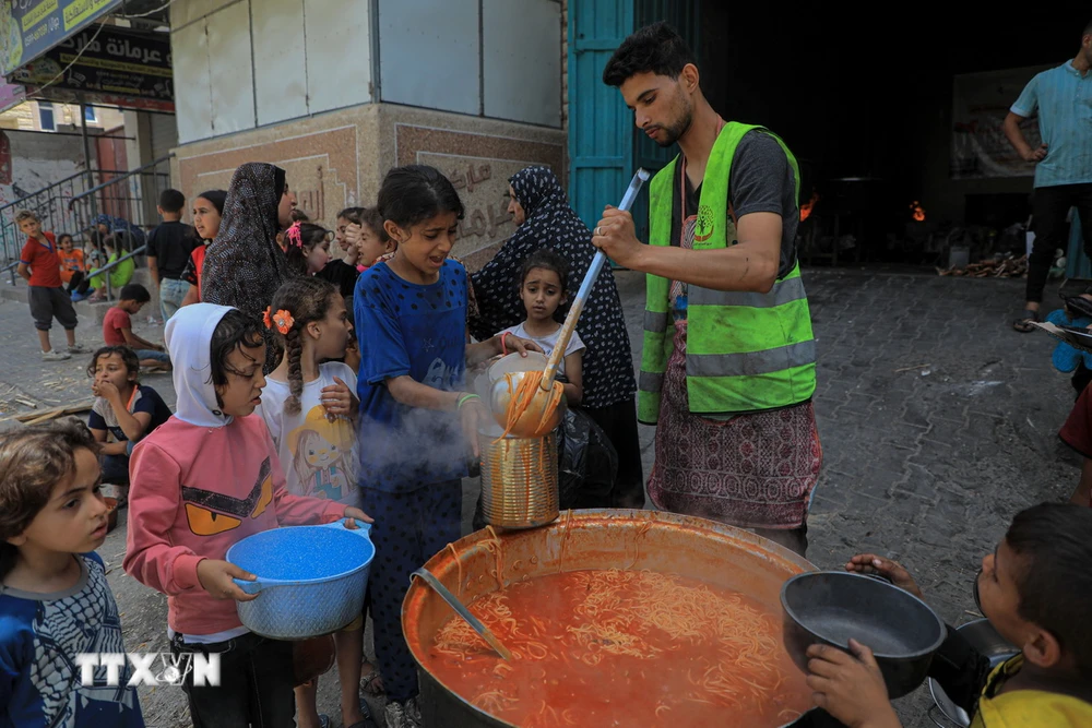 Các em nhỏ nhận thực phẩm cứu trợ tại thành phố Rafah, Dải Gaza. (Ảnh: THX/TTXVN)