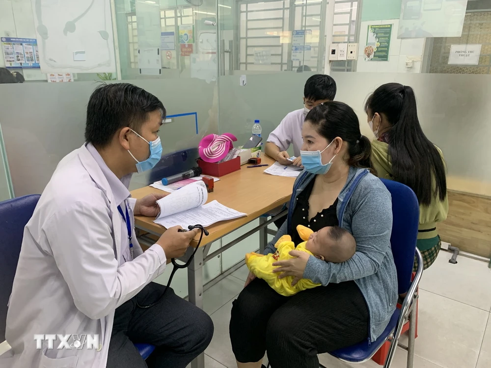 Phụ huynh đưa trẻ đi tiêm vaccine phòng bệnh sởi. (Ảnh: Đinh Hằng/TTXVN)