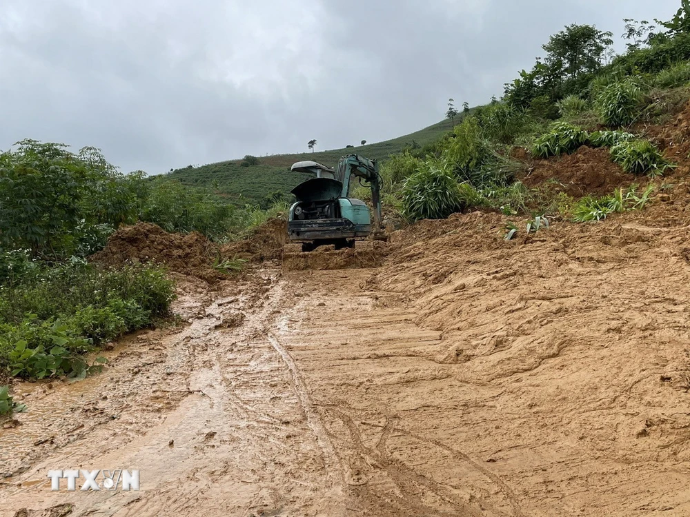 Cơ quan chức năng tiến hành dọn lượng đất, đá bị sạt lở tại Km9+200 của Tỉnh lộ 674, đoạn qua xã Sa Sơn (huyện Sa Thầy, tỉnh Kon Tum). (Ảnh: TTXVN phát)