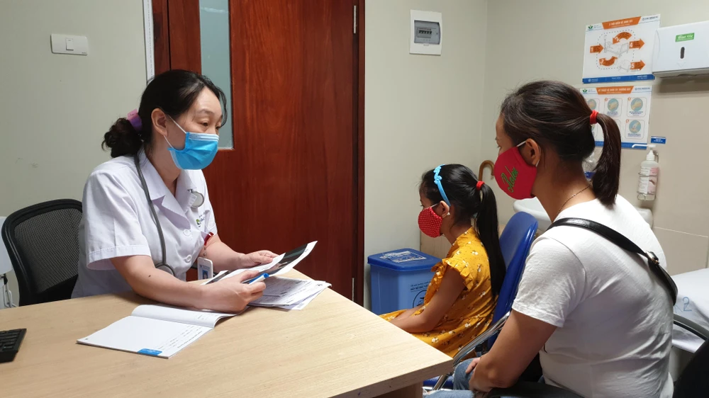 Tiến sỹ Nguyễn Ngọc Khánh khám cho một bé gái dậy thì sớm. (Ảnh: T.G/Vietnam+)