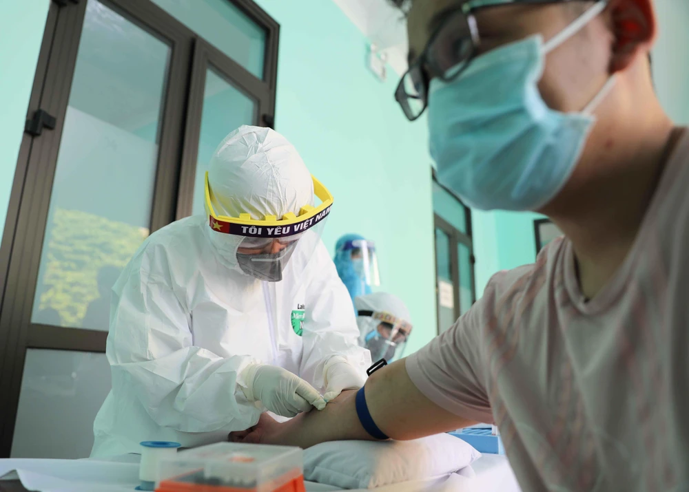 Nhân viên y tế lấy mẫu máu để xét nghiệm nhanh cho người dân tại Trạm Y tế phường Dịch Vọng, quận Cầu Giấy. (Ảnh: Thanh Tùng/TTXVN)