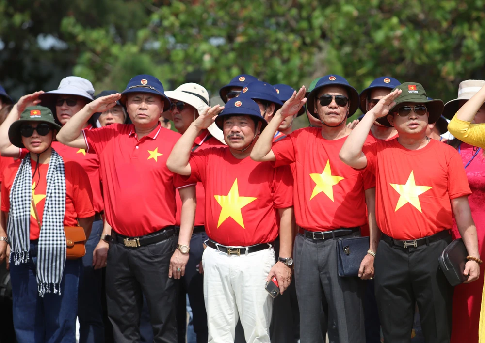 Bà con Kiều bào cùng các đại biểu làm lễ chào cờ tại đảo Trường Sa. (Ảnh: Hồng Sơn/Vietnam+)
