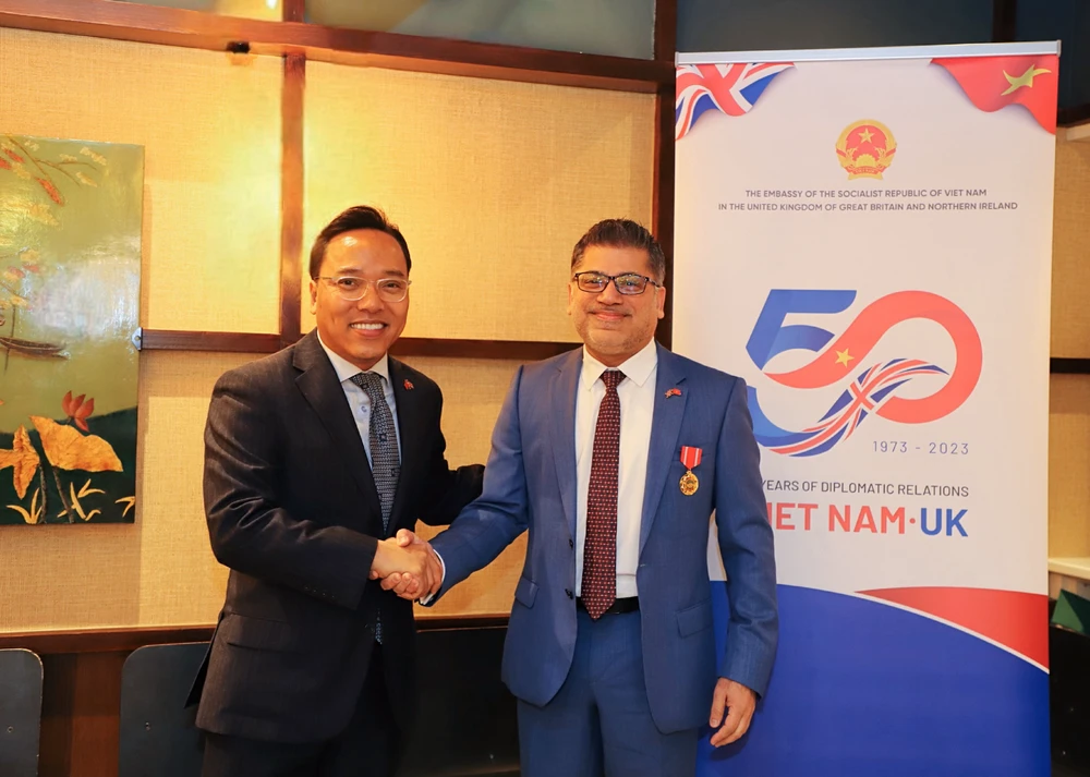 Đại sứ Việt Nam tại Vương quốc Anh Nguyễn Hoàng Long công bố và trao cho Chủ tịch kiêm Tổng Giám đốc AstraZeneca Việt Nam tại Anh. (Ảnh: PV/Vietnam+)