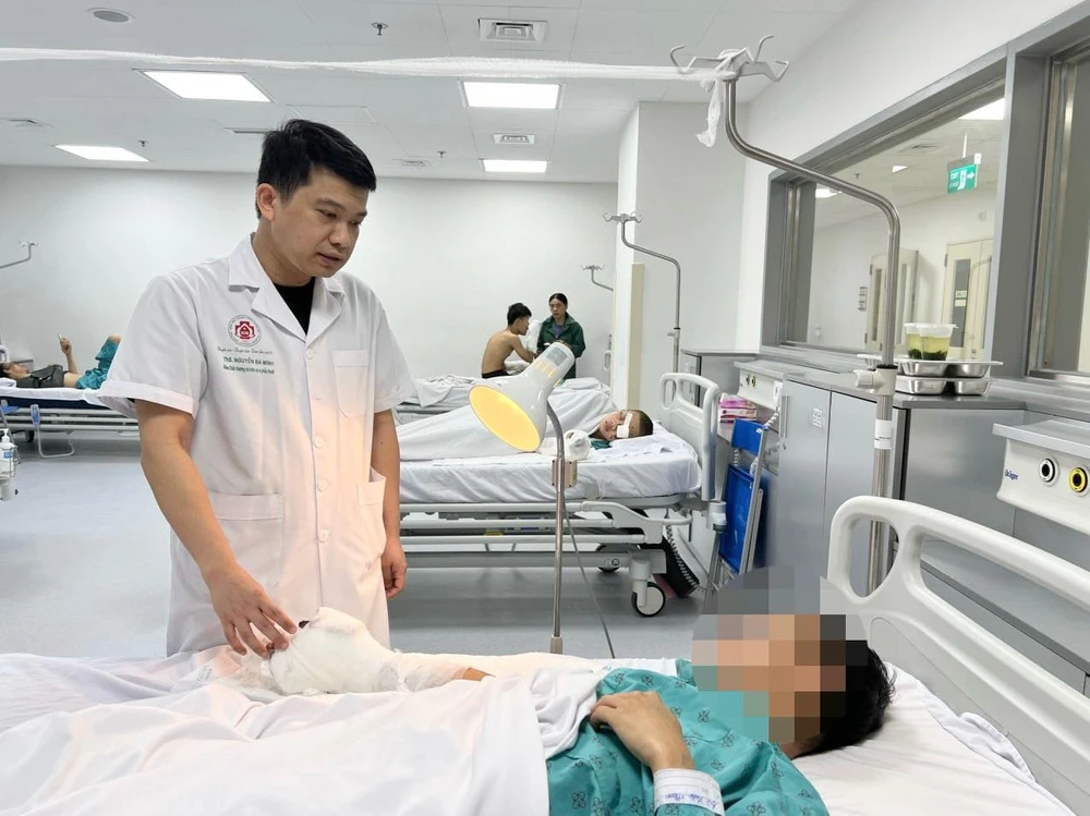 Bác sĩ Bệnh viện Trung ương Quân đội 108 khám, theo dõi sức khoẻ cho một bệnh nhân tại nạn do pháo nổ. (Ảnh: PV/Vietnam+)