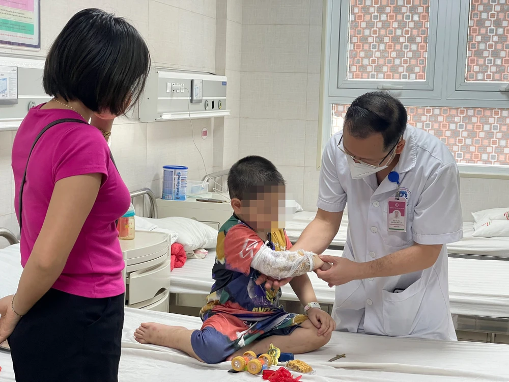 Bác sĩ Nguyễn Đức Lân - Trưởng khoa Ngoại nhi tổng hợp thăm khám cho bệnh nhi C. trước khi xuất viện. (Ảnh: PV/Vietnam+) 