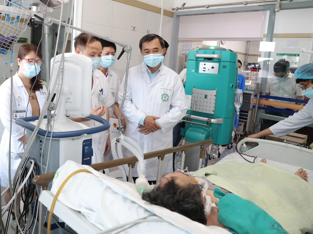 Thứ trưởng Bộ Y tế Trần Văn Thuấn thăm nạn nhân nặng nhất của vụ cháy nhà trọ đang điều trị tại Trung tâm Hồi sức, Bệnh viện Bạch Mai. (Ảnh: PV/Vietnam+)