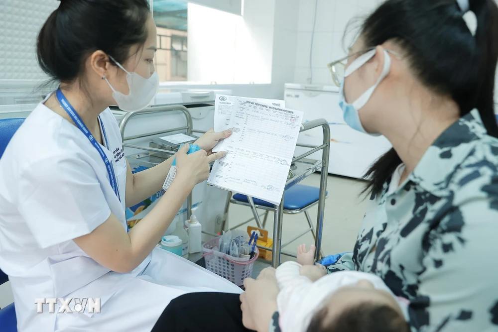 Nhân viên y tế hướng dẫn người dân về vaccine trước khi tiêm cho trẻ. (Ảnh: Minh Quyết/TTXVN) 