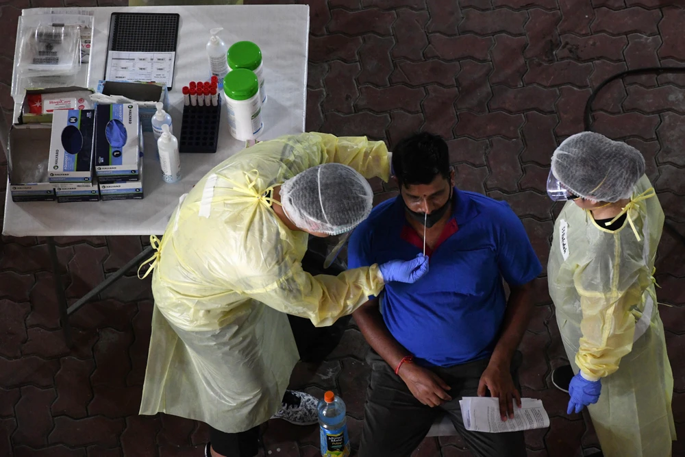 Nhân viên y tế lấy mẫu xét nghiệm COVID-19 cho công nhân tại Singapore. (Ảnh: AFP/TTXVN)