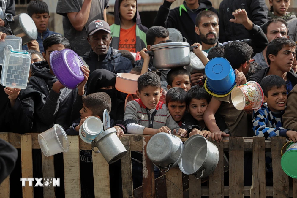 Người dân chờ nhận thực phẩm cứu trợ tại thành phố Rafah, Dải Gaza. (Ảnh: THX/TTXVN)