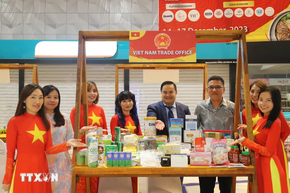 Tham tán Thương mại Lê Phú Cường (thứ tư từ bên phải) và ông Wong Hon Wai - Giám đốc Điều hành, phụ trách lĩnh vực du lịch và kinh tế sáng tạo của Penang (thứ ba từ bên phải) cùng kiều bào tại quầy hàng giới thiệu sản phẩm của Thương vụ Việt Nam tại Malaysia. (Ảnh: Hằng Linh/TTXVN)
