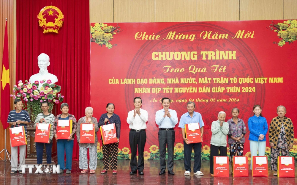 Phó Thủ tướng Lê Minh Khái và Bí thư Tỉnh ủy An Giang Lê Hồng Quang tặng quà Tết cho các hộ gia đình chính sách có hoàn cảnh khó khăn và công nhân, lao động có hoàn cảnh khó khăn trên địa bàn tỉnh An Giang. (Ảnh: Công Mạo/TTXVN)