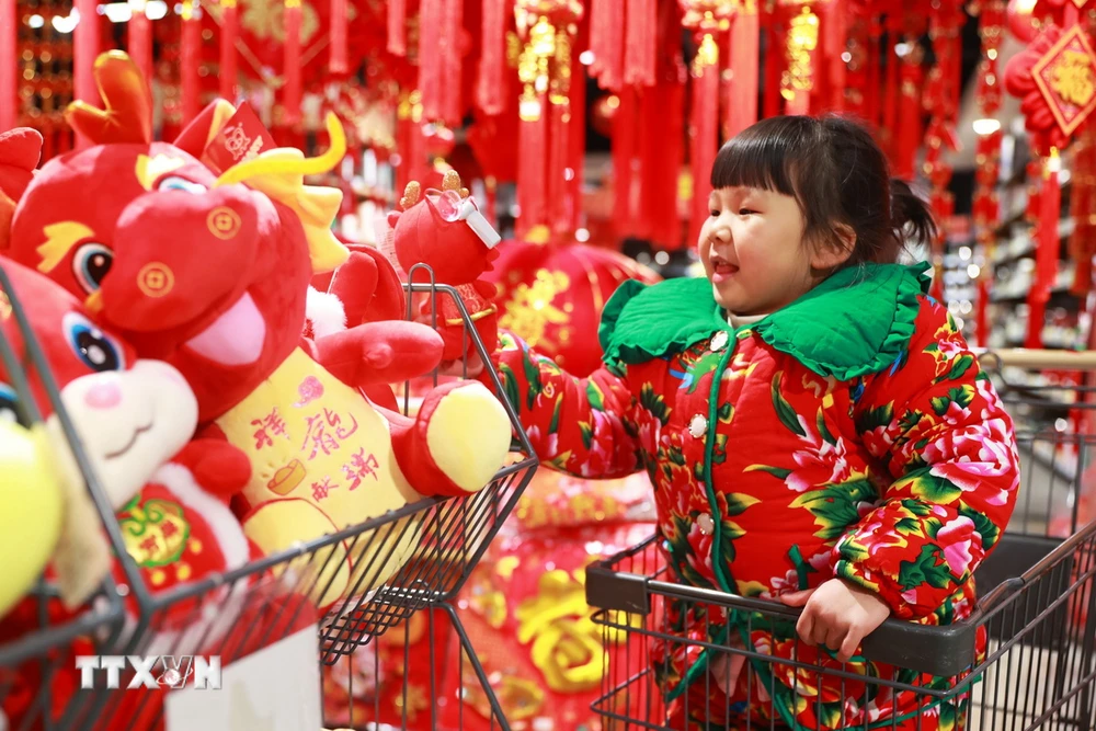 Em nhỏ thích thú ngắm nhìn đồ trang trí Tết Nguyên đán Giáp Thìn tại siêu thị ở tỉnh Quý Châu, Trung Quốc. (Ảnh: THX/TTXVN)
