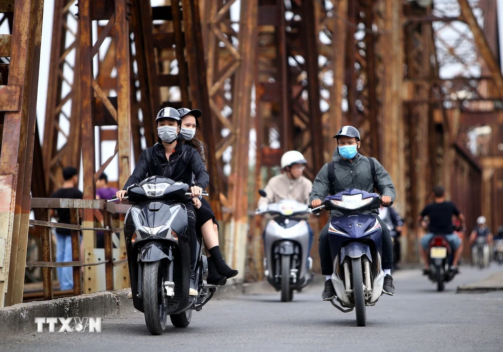 Người dân với trang phục áo ấm đi trên cầu Long Biên (Hà Nội) vào sáng sớm. (Ảnh: Danh Lam/TTXVN)