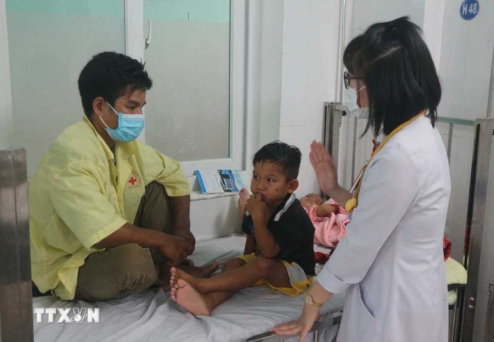 Bác sỹ kết hợp thăm, khám với tuyên truyền cho phụ huynh về cách phòng, chống bệnh trên trẻ em. (Ảnh: Dư Toán/TTXVN)
