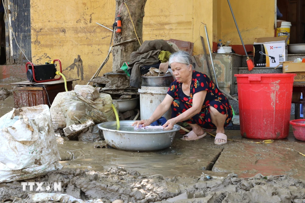 Người dân sinh sống trên 2 tuyến phố Thanh Niên và Trần Hưng Đạo, thành phố Yên Bái, dần trở lại cuộc sống thường nhật cho dù đường vẫn còn chưa hết ngập, chiều ngày 14/9. (Ảnh: Tuấn Anh/TTXVN)