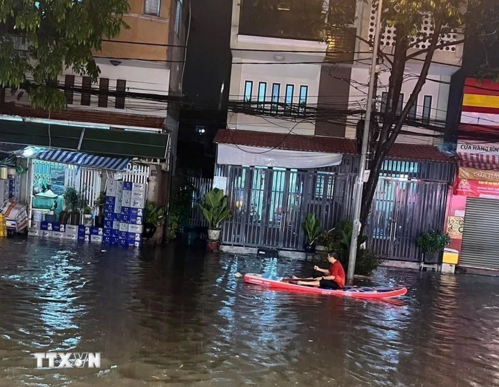 Người dân phải dùng thuyền để di chuyển tại khu vực ngã ba cống trên đường Thích Quảng Đức, thành phố Thủ Dầu Một, tỉnh Bình Dương. (Ảnh: TTXVN phát)